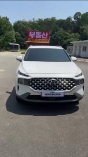 Белый Hyundai Santa Fe 2020, вид спереди на стоянке в Южной Корее — осмотр при покупке, видны вывески с корейскими буквами.