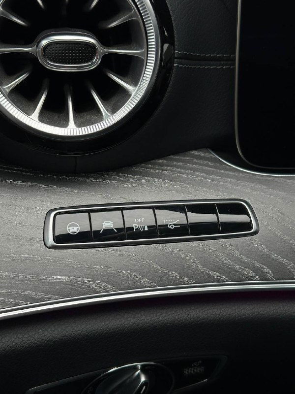 Блок кнопок управления и панель с переключателями в салоне Mercedes CLS450 AMG Line, подсветка и текстура покрытия, детали отделки видны на фото для покупателя.