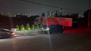 Вид крупным планом на грузовой тягач и прицеп для автовоза ночью на стоянке в порту/логистической зоне Южной Кореи.