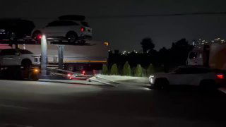 Широкий ночной кадр автовоза в движении или на стоянке с загруженными автомобилями и освещением, подготовка к отправке судном.