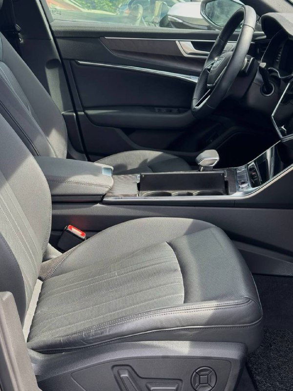 Переднее пассажирское кресло и центральный тоннель Audi A6 2020 — тканевая обивка, подлокотник и элементы управления.