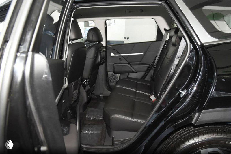 Вид на задний ряд сидений Hyundai Mufasa: трёхместная компоновка, чёрная обивка и достаточный простор для пассажиров, общий ракурс через открытую заднюю дверь.