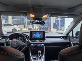 Фото салона Toyota RAV4 2020: панель приборов, мультимедиа экран и руль; общий вид передней части интерьера в шоуруме.