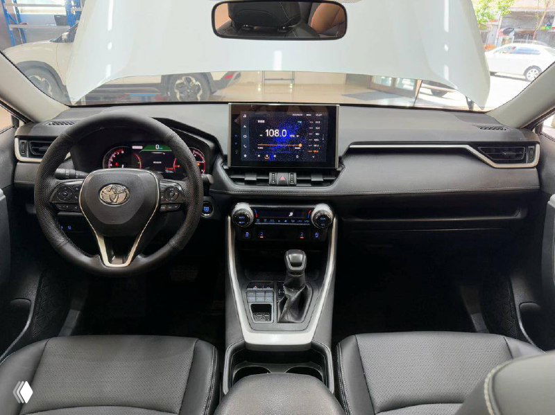 Фото салона Toyota RAV4 2021: передняя панель, мультимедиа экран и руль; состояние интерьера и приборная панель вблизи.