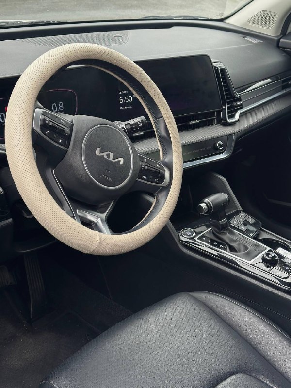 Салон KIA Sportage 2022 — вид на руль с оригинальным логотипом KIA и переднюю панель; кожа чехла руля, мультируль и экран приборов.
