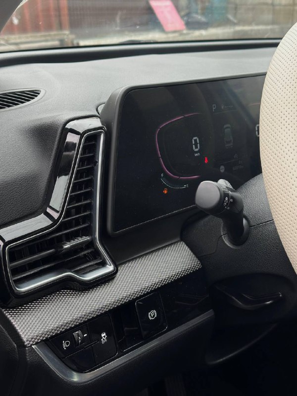 Угол салонной панели KIA Sportage и элемент вентиляционного сопла рядом с приборной панелью; видна текстура торпеды и части руля.