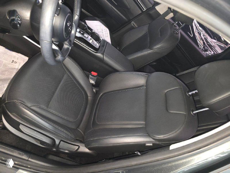 Переднее пассажирское сиденье и водительское кресло Hyundai Tucson 2021 — чёрная кожаная или кожзамённая обивка, вид с открытой дверью.