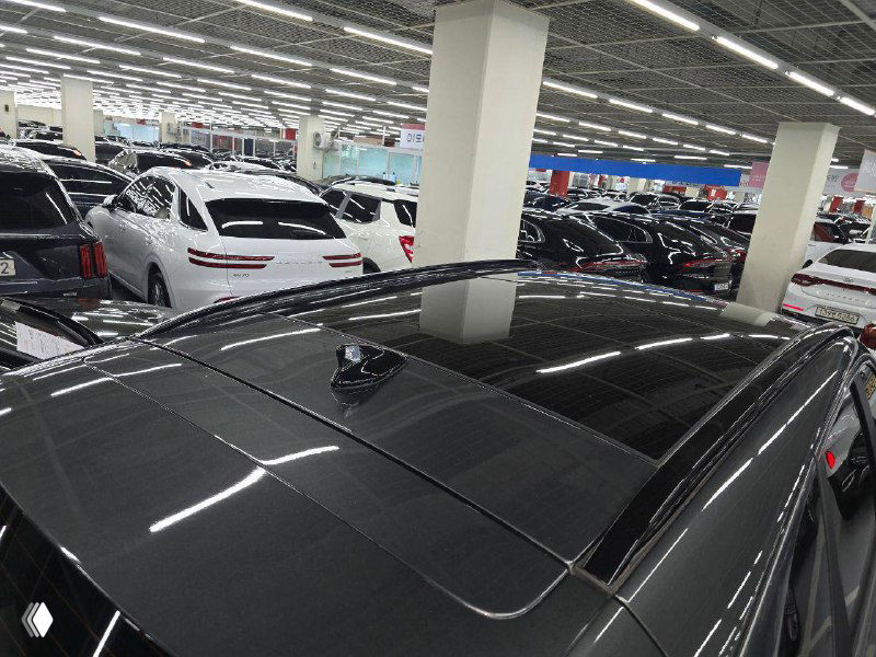 Панорамная крыша и крыша автомобиля Hyundai Tucson 2021 — вид сверху с антенной и отражением света в шоу-руме на стойках потолка.