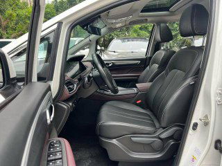 Фронтальный вид на передние кресла и пространство водителя GAC Trumpchi M6, видна отделка сидений, дверные панели и общий комфорт салона для пассажиров и водителя.