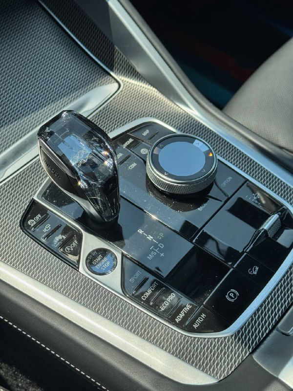 Крупный план рычага переключения передач и управляющего колеса iDrive на центральной консоли BMW X6 — фокус на отделке и элементах управления.