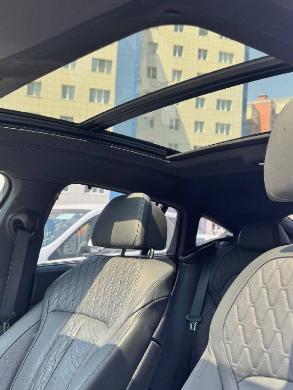 Салон BMW X6 с панорамной крышей: вид на передние сиденья и крупное стеклянное панорамное окно над пассажирским отсеком.