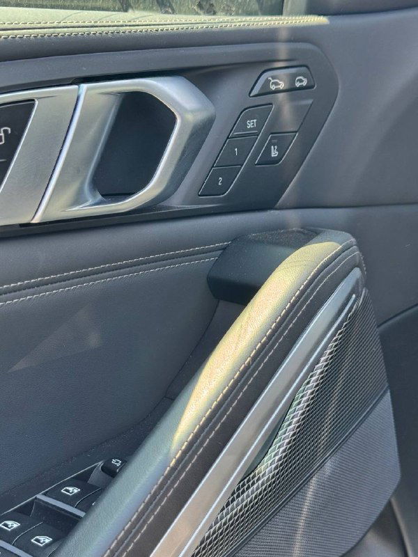 Панель дверей BMW X6 с электронными кнопками регулировки сиденья и декоративной отделкой, акцент на мелких деталях салона.