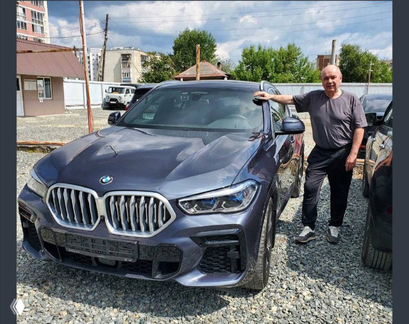 Фронтальный ракурс серого BMW X6, крупный план передней части и решётки радиатора, автомобиль без государственных номеров на стоянке.