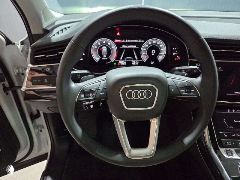 Руль Audi с логотипом, цифровая приборная панель и элементы управления на руле — чёткая фотография водительского места автомобиля.