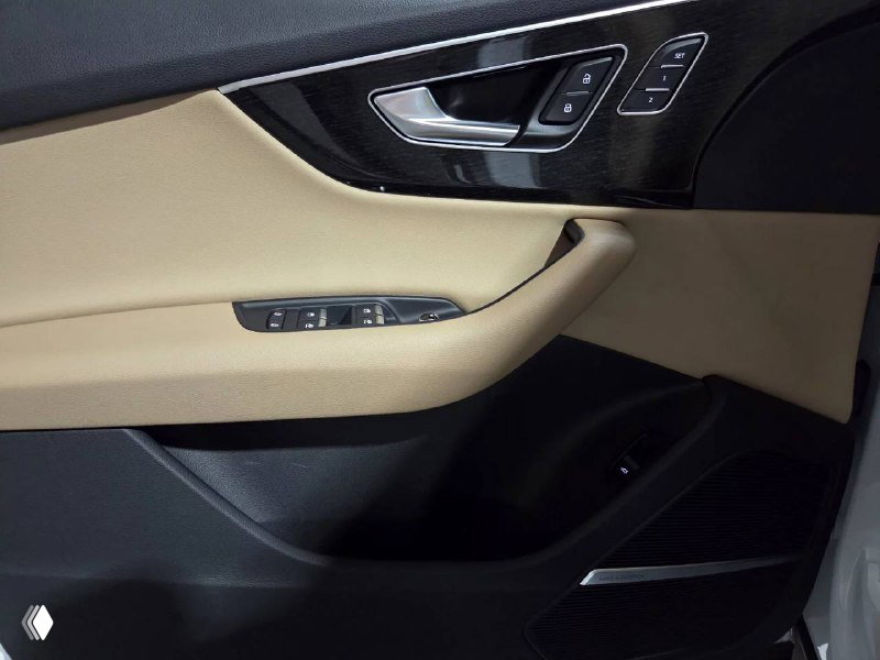 Дверная карта передней пассажирской двери Audi Q7 с элементами управления сиденьями и декоративной вставкой тёмного цвета.