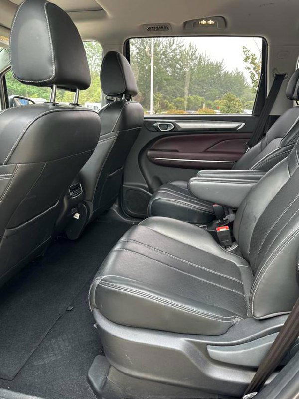 Второй ряд сидений GAC Trumpchi M6: кожаная обивка, пространство для ног и общий вид посадочных мест с открытым боковым окном.