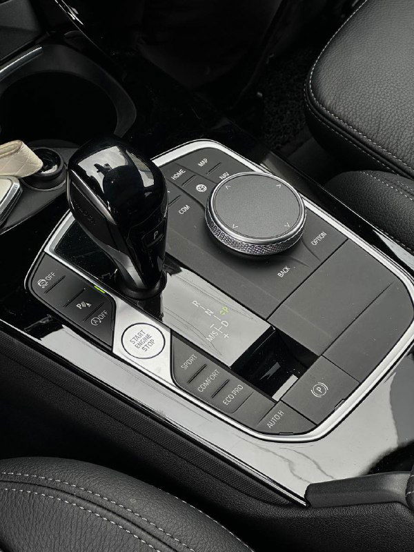 Селектор коробки передач и центральный контроллер iDrive BMW 120i, кнопки режимов движения и хромированные детали вокруг консоли.