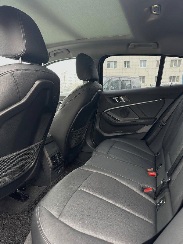 Задний ряд сидений BMW 120i: три посадочных места, карманы на спинках и общий вид пространства для пассажиров.