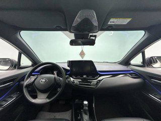 Вид салона Toyota C-HR 2021: панорамная приборная панель, руль, мультимедийный экран и обзор фронтального ветрового стекла с зеркалом заднего вида.