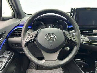 Крупный план рулевого колеса Toyota с элементами управления на спицах; вид центральной консоли и части приборной панели, без повреждений.