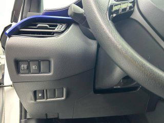 Кнопки и органайзер в зоне водителя Toyota C-HR: блок переключателей слева от руля, панель управления и отделка рулевой колонки, чистое состояние.