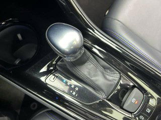 Рычаг коробки передач и центральный тоннель Toyota C-HR 2021: вариаторный селектор, стояночный тормоз, декоративная отделка и подстаканники, аккуратный вид.