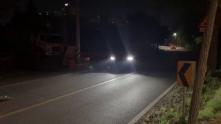 Ночной кадр дороги с фарами встречных машин и грузовиками — часть видеорепортажа о перевозке автомобилей в порт и ночных манёврах.