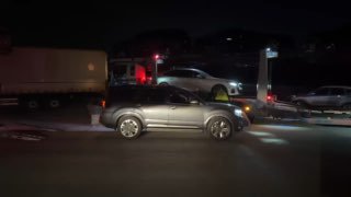 Съёмка погрузки: легковой автомобиль на пандусе автовоза, отражения фар и рабочее освещение в ночное время при отправке в Пусан.