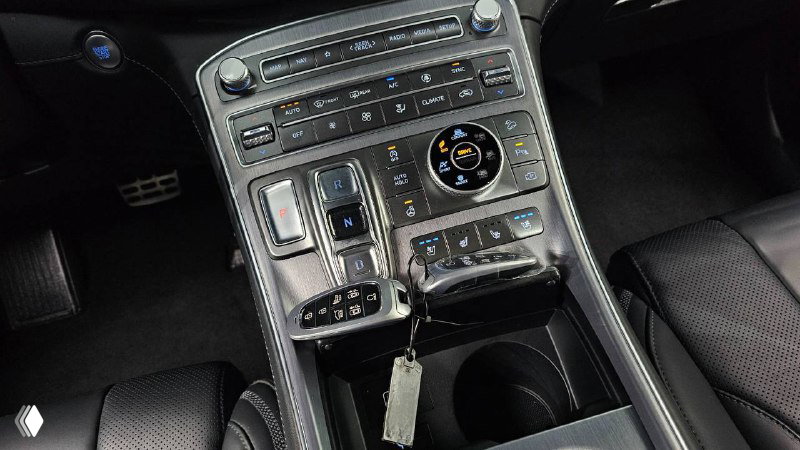 Крупный план центральной консоли Hyundai Santa Fe Calligraphy 2020 с селектором коробки, клавишами управления и связкой ключей на подстаканнике.