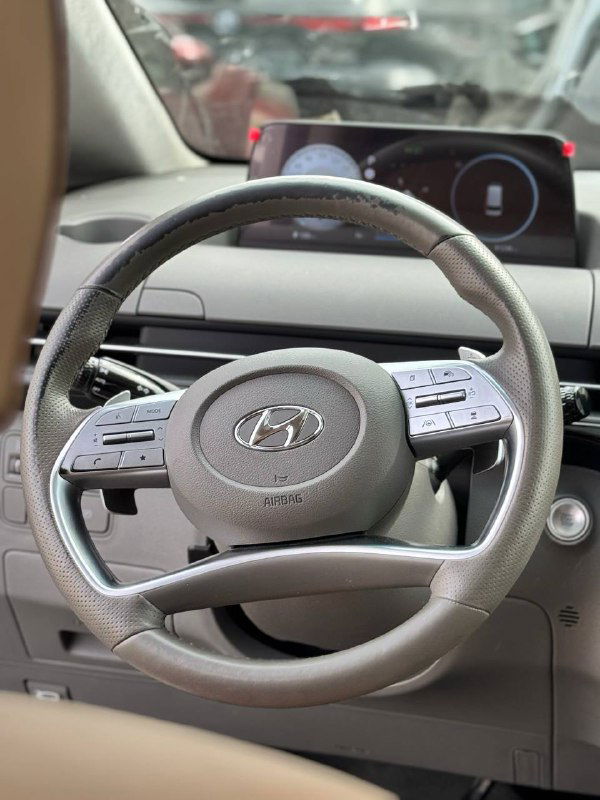 Крупный план рулевого колеса Hyundai Staria: кожаная отделка, кнопки мультируля и эмблема Hyundai на центральной части руля.