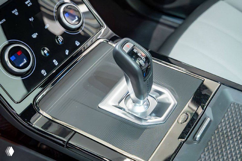 Крупный план селектора коробки передач Range Rover Evoque 2021 и декоративных элементов центральной консоли, хромированные детали и панели.