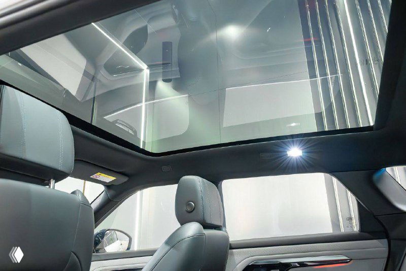 Панорамная крыша и потолок салона Range Rover Evoque 2021 с подсветкой, вид на передние подголовники и стеклянную панель крыши.