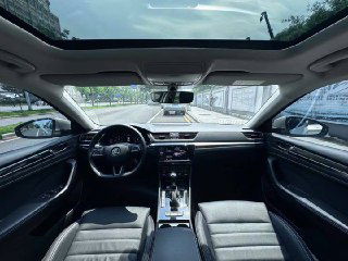 Интерьер Skoda Superb 2021: панорамный вид салона спереди, руль, большая консоль, панорамная крыша и вид на лобовое стекло, аккуратный салон.