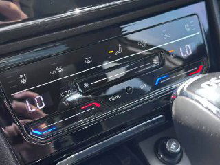 Крупный план панели климат-контроля и сенсорных кнопок Skoda Superb: стильная глянцевая панель с подсветкой и обозначениями режимов.