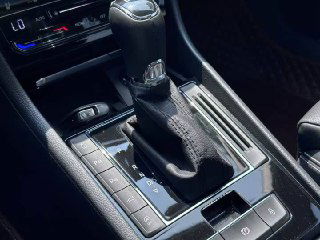 Крупный план селектора коробки передач и центральной консоли Skoda Superb 2021: рычаг, отделка, кнопки вокруг селектора и подстаканник.