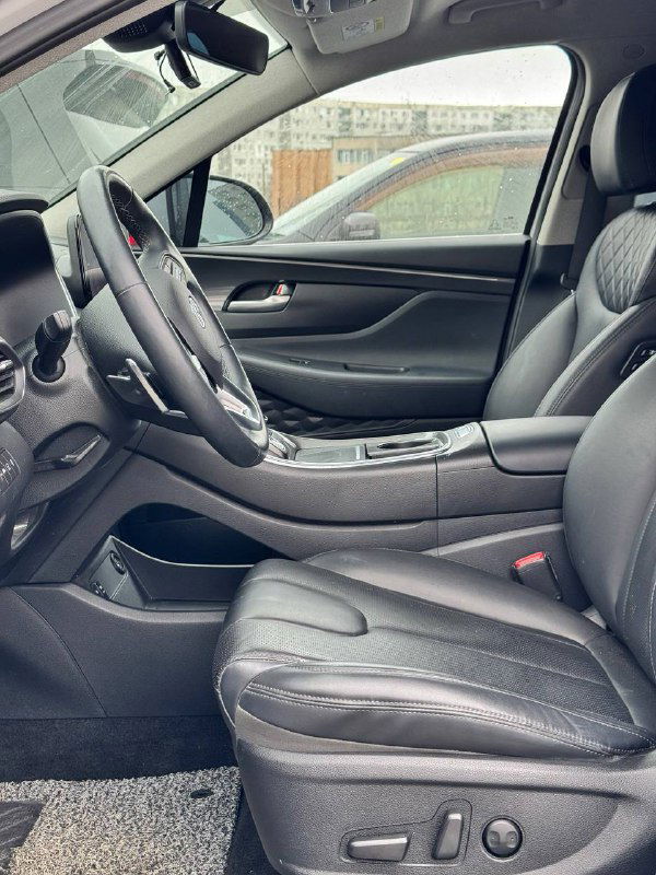 Вид водительского сиденья и центральной консоли Hyundai Santa Fe: кожаная обивка, регулировки сиденья и пространство между рядами.