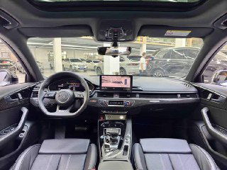 Салон Audi A4L 2022: панорамный вид на рулевую колонку, центральную консоль и мультимедийный экран, чёрная отделка и современная приборная панель на фоне автоцентра.