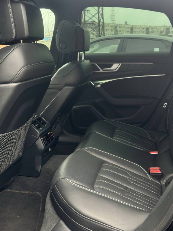 Задний ряд сидений Audi A6: вид на места для пассажиров, кожаная обивка, ножные просторы и вентиляционные решётки между передними сиденьями.