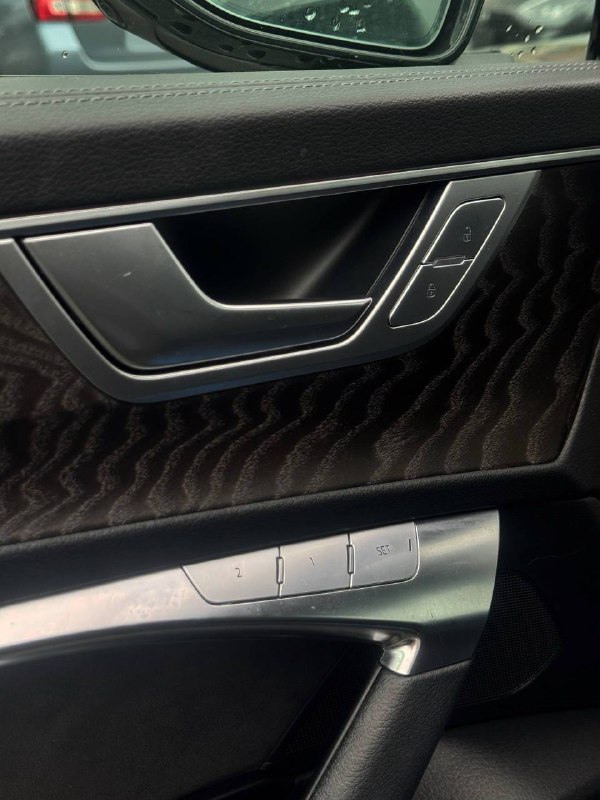 Деталь дверной панели Audi A6: отделка, элементы управления стеклоподъёмниками и настройками сиденья, вид крупным планом на текстуру материала.