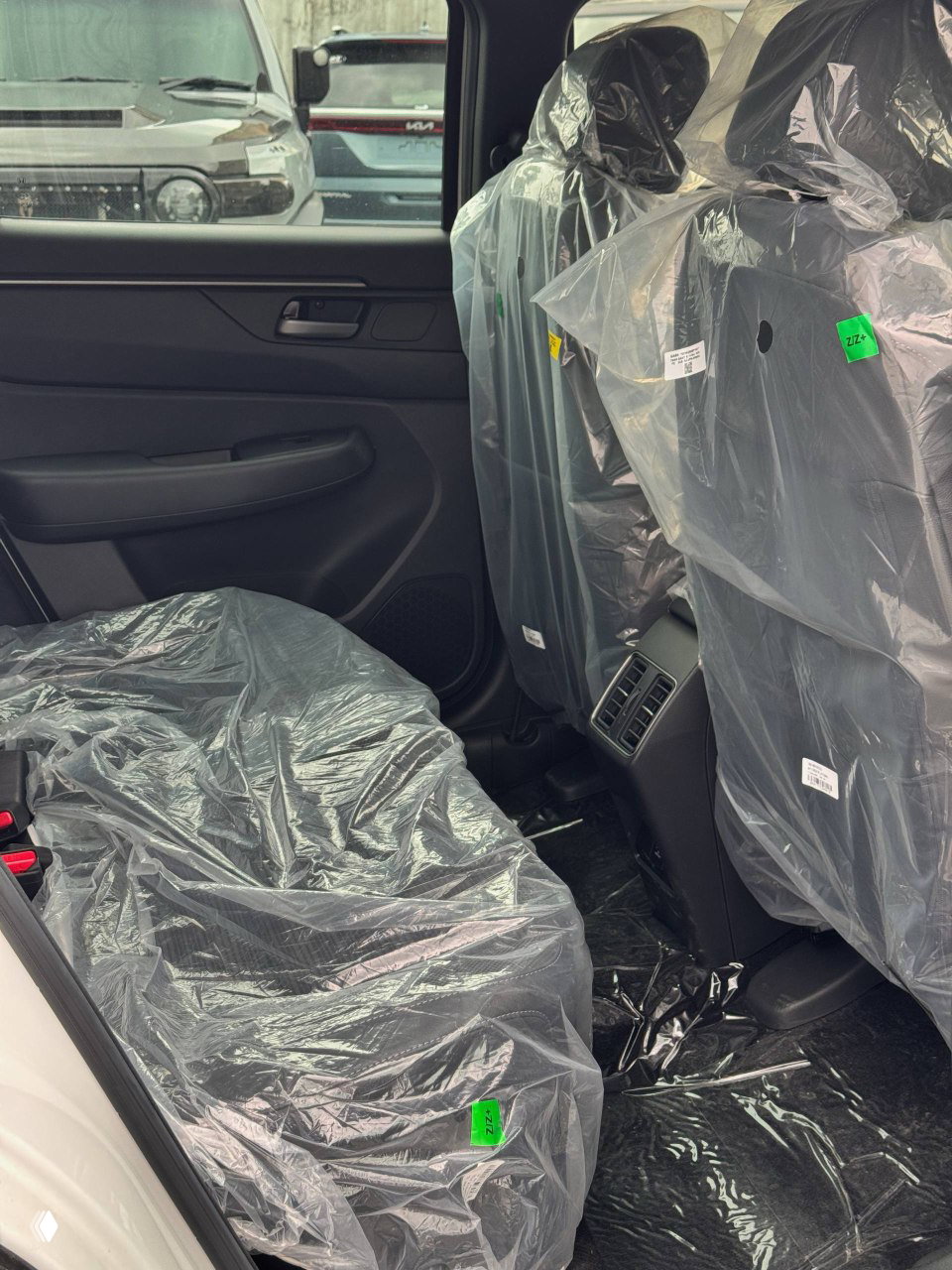 Задние сиденья Honda WR‑V в плёнке, вид на пространство для ног и вентиляционные отверстия для задних пассажиров.