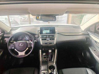 Салон Lexus NX200: вид на панель управления, руль и центральную консоль; интерьер в тёмной отделке, состояние сидений видно на снимке.