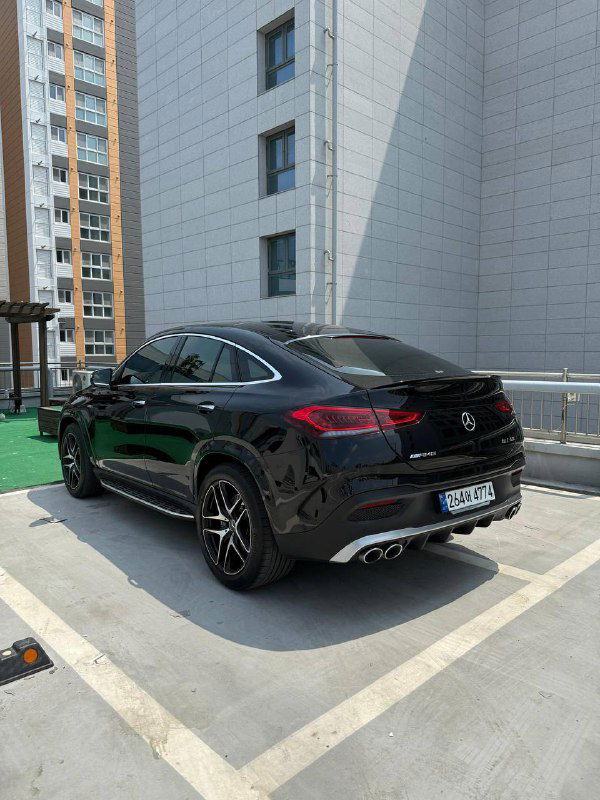 Вид сзади и сбоку на черный Mercedes GLE AMG53 2023 года, заметны спортивные диски и двойной выхлоп — фото автомобиля после покупки в Корее.