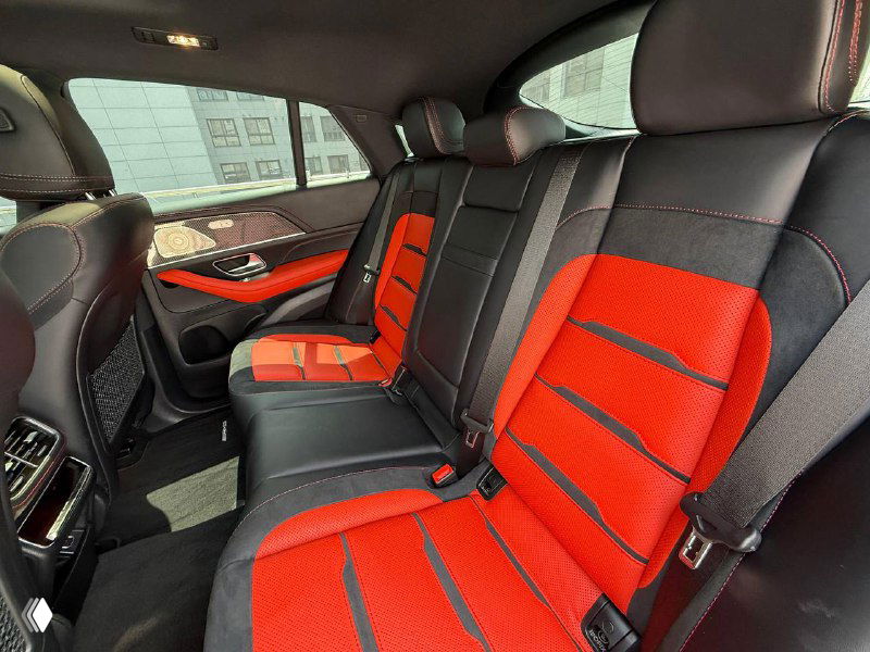 Задние сиденья Mercedes GLE AMG53 2023 с красными вставками и трехместной конфигурацией, фото демонстрирует свободное пространство и обивку салона.