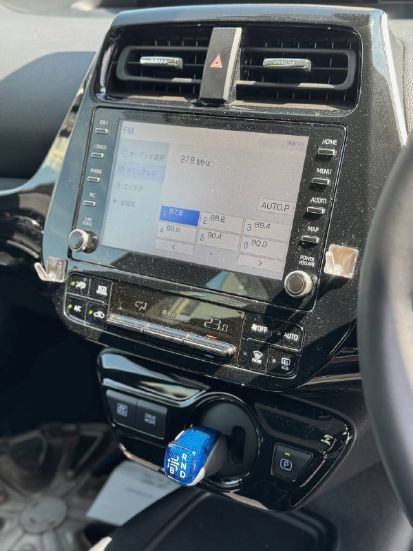 Центральная консоль Toyota Prius с сенсорным дисплеем мультимедиа и селектором трансмиссии на фоне приборной панели.