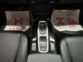 Ближайший план селектора и кнопок управления передачами в Honda Crider, вид на подлокотник и пространства между передними сиденьями в салоне.