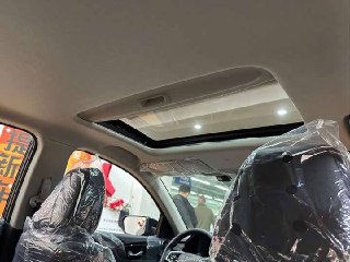 Встроенный люк в крыше Honda Crider — вид из салона на панорамный люк, закрытые пластиковые чехлы на сиденьях и верхнюю обшивку потолка.