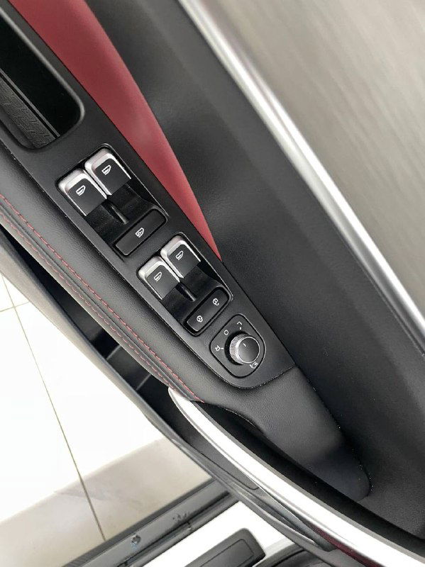 Фрагмент панели двери с кнопками управления стеклоподъемниками и боковым зеркалом в белом Geely Coolray — крупный план функциональных элементов и отделки.