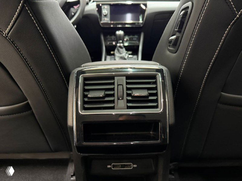 Крупный план вентиляционных решёток и отсека для мелочей на задней панели Skoda Superb, видна отделка и USB-порт.