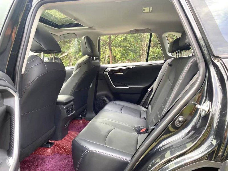 Задний ряд Toyota Wildlander: открытая дверь, чёрные кожаные сиденья и пространство для пассажиров, вид сбоку на салон.