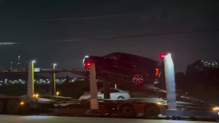 Сцена загрузки: вид сзади на прицеп, на верхней палубе виден джип, нижняя палуба с компактным кроссовером, ночь и освещение порта в кадре.